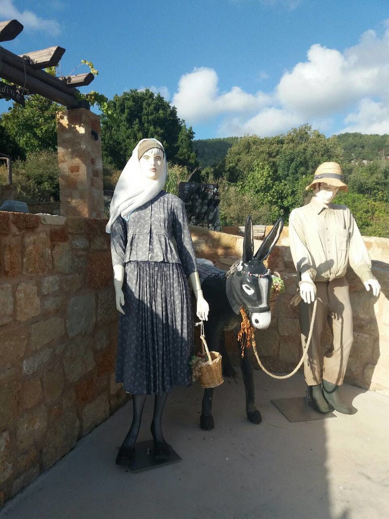 a couple of dolls with a donkey doll in front at 'Piperis Winery' outside